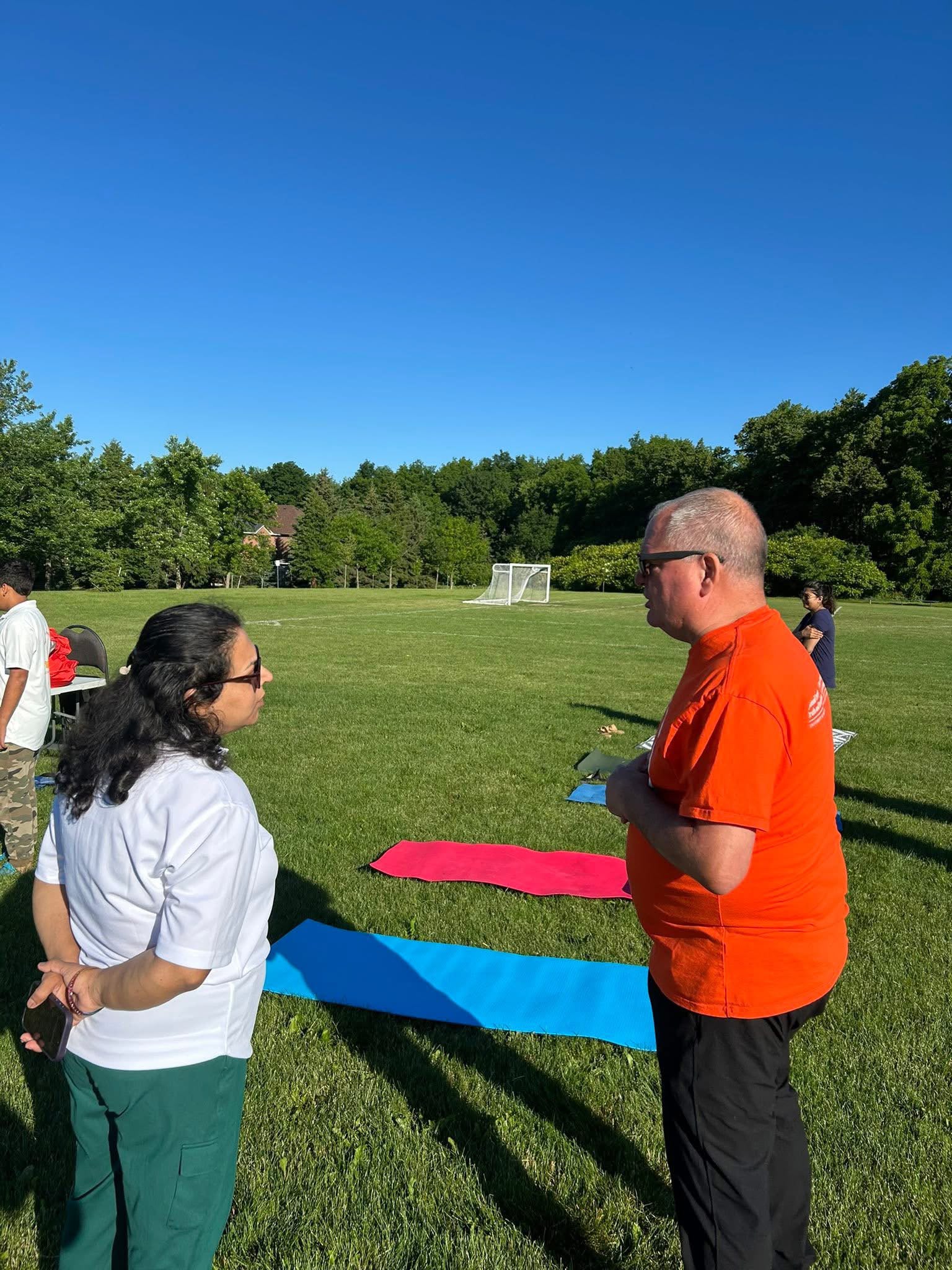 Shashi Singh engaging with a community member at an outdoor park event on a sunny day