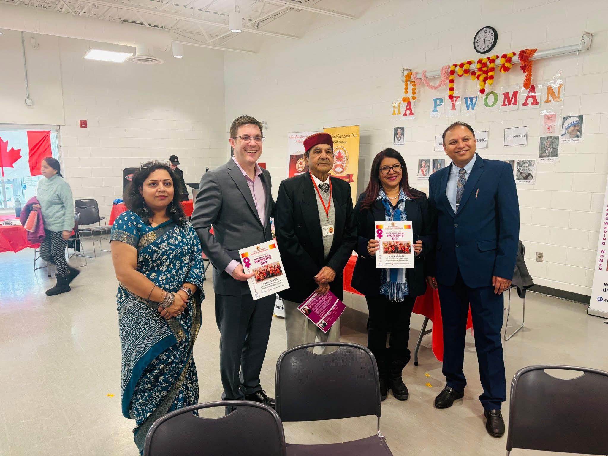 International Women's Day celebration – Shashi Singh with community dignitaries holding event flyers
